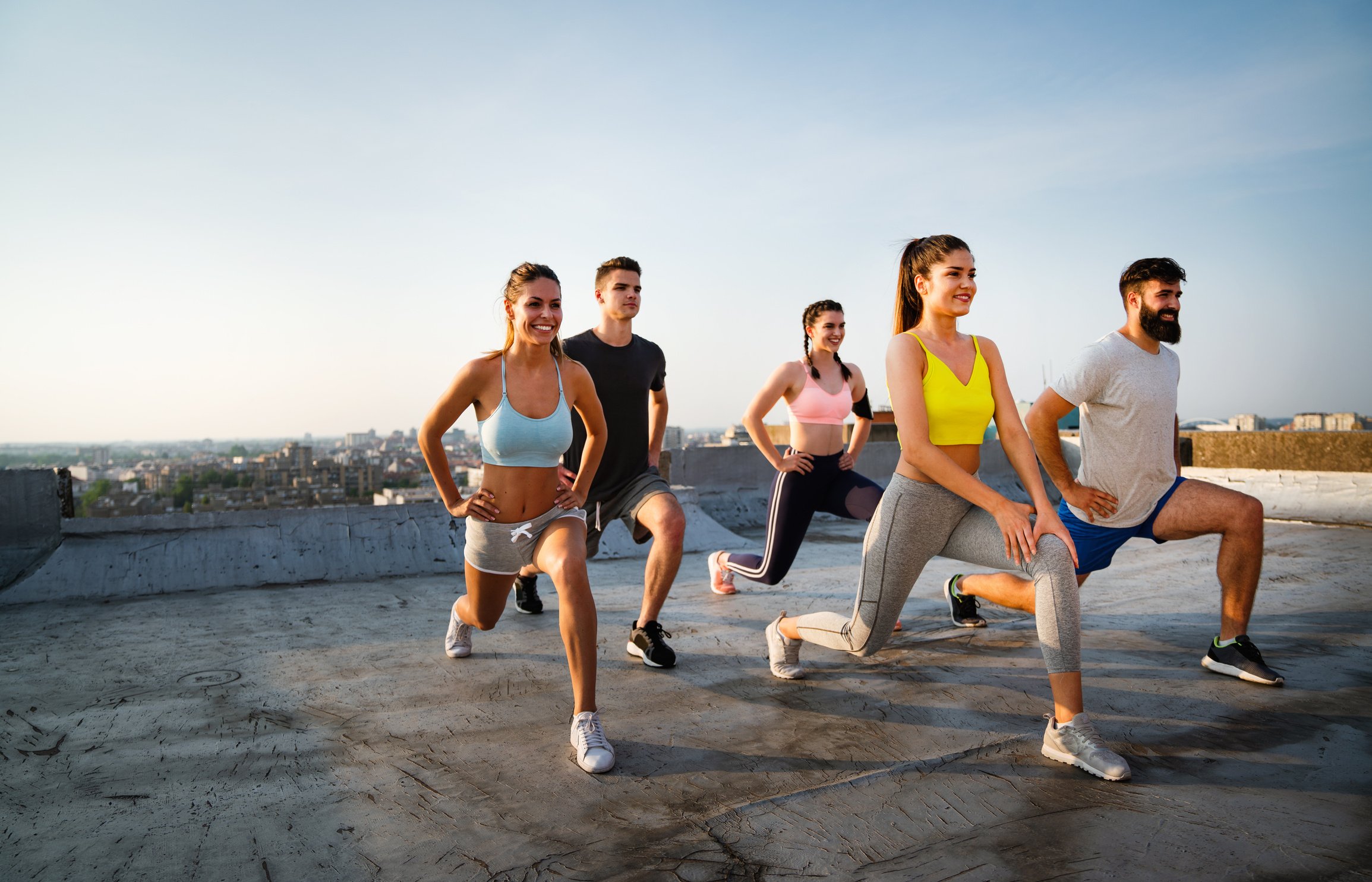 Group of cheerful fit fitness team exercising together outdoor